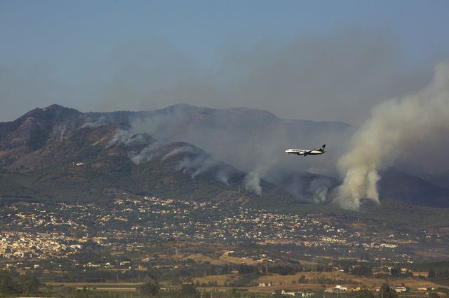 A plane flies over a forest fire in Andalusia. [Alvaro Cabrera - Keystone/EPA]