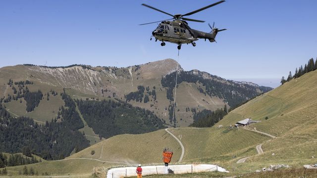 Un hélicoptère Super Puma de l'armée suisse ravitaille en eau l'alpage de Tissiniva, le 10 août 2022, à Charmey.  [Cyril Zingaro - KEYSTONE]