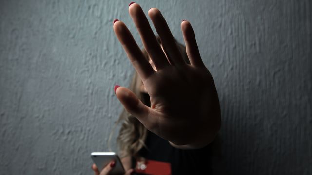 Une femme tenant un téléphone portable dit 'stop' de la main. [Burdun - Depositphotos]