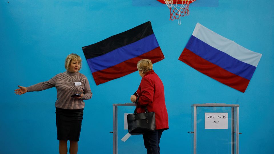 Une membre de la commission électorale montre la voie à un électeur dans un bureau de vote lors d'un référendum sur l'adhésion de la République populaire de Donetsk (RPD) autoproclamée à la Russie, à Donetsk. [Alexander Ermochenko - reuters]