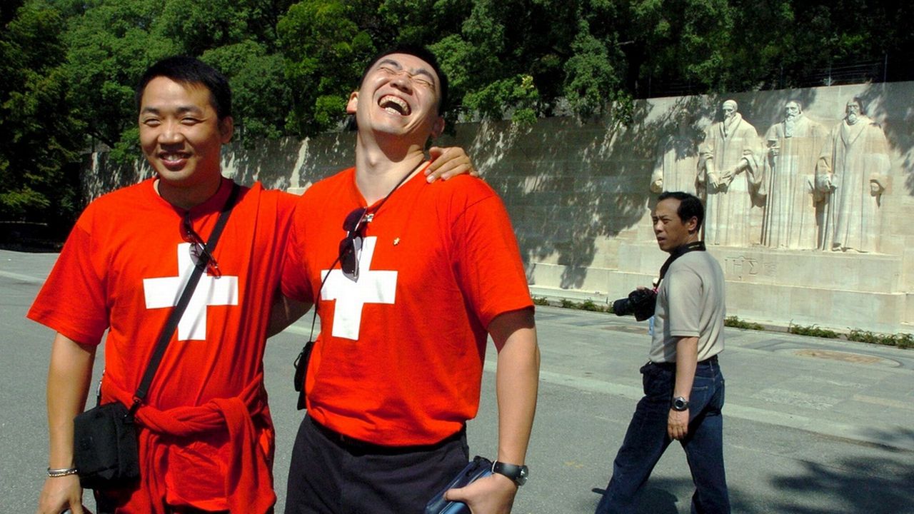 Des touristes chinois photographiés à Genève devant le Mur des Réformateurs. [Martial Trezzini - Keystone]
