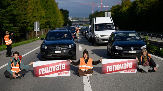 Des militants écologistes membres de Renovate Switzerland se sont assis sur la route lors d'une action de blocage de l'autoroute A1 à l'entrée de Lausanne, mardi 4 octobre 2022. [Laurent Gillieron - KEYSTONE]