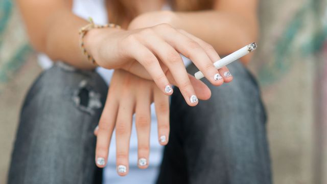 Gros plan sur la main d'une adolescente tenant une cigarette. [SolidPhotos - Depositphotos]
