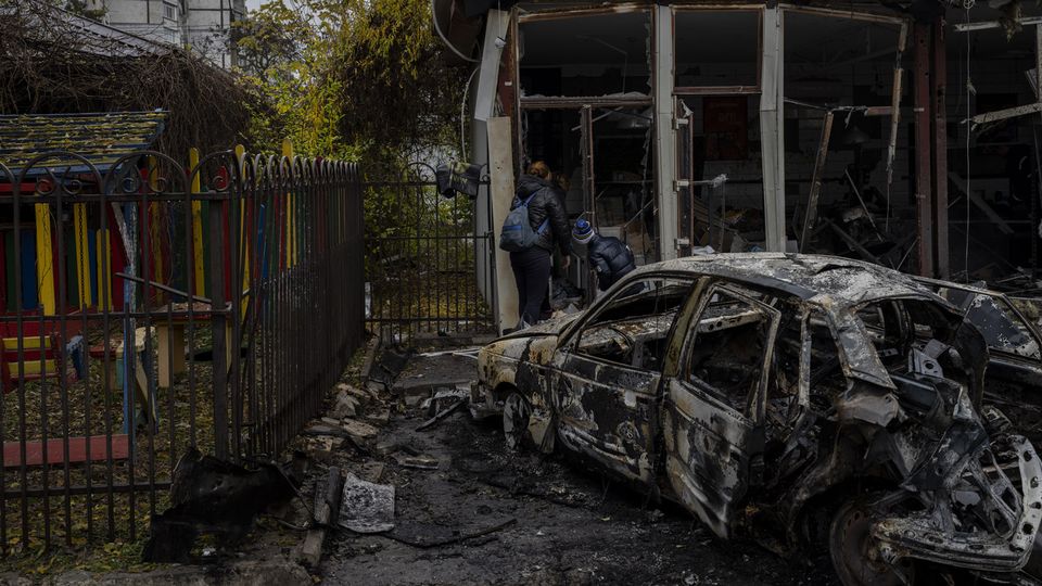Des habitants inspectent un magasin détruit un jour plus tôt lors d'une attaque russe à Kherson, dans le sud de l'Ukraine, le vendredi 25 novembre 2022. [AP Photo/Bernat Armangue - Keystone]