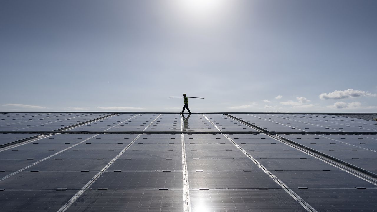Le solaire a la cote. Ici: l'installation de panneaux photovoltaïques par un ouvrier en Valais en octobre 2022. [Gaetan Bally - KEYSTONE]