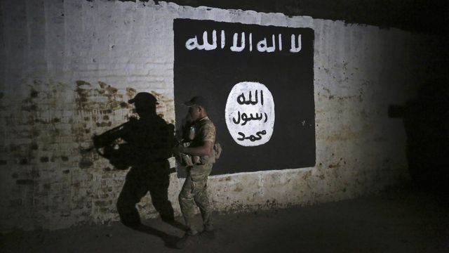 Un soldat irakien devant une bannière du groupe Etat islamique, en 2017 à Mossoul. [Khalid Mohammed - AP/Keystone]