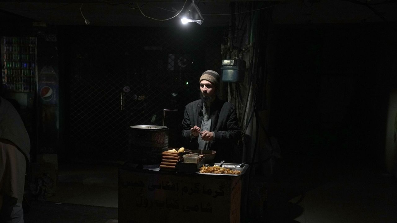 Un vendeur utilise des lampes alternatives pour s'éclairer dans son étal de frites sur un marché pendant une panne d'électricité nationale, à Islamabad, au Pakistan, le lundi 23 janvier 2023. [Anjum Naveed - Keystone]
