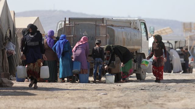 Des réfugiés syriens remplissent un réservoir d'eau au camp de Kalbeet, dans le nord d'Idlib, le 29 octobre 2022. [Yahya Nemah - Keystone]