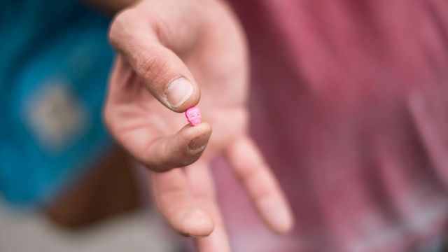 Un homme montre une pilule de MDMA, une drogue de la catégorie des amphétamines, connue pour ses effets stimulants et hallucinants (image d'illustration). [Ennio Leanza - Keystone]