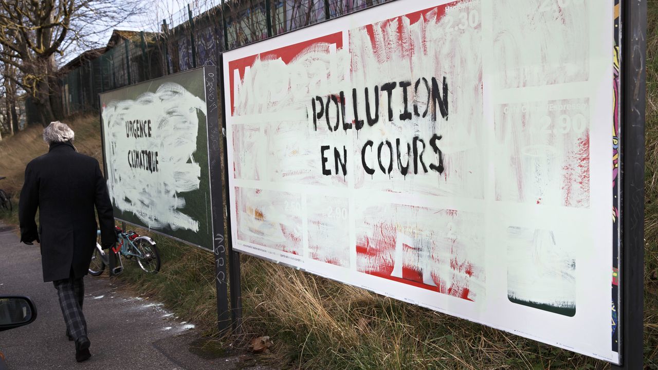 Affiches publicitaires recouvertes de peinture avec le message "Pollution en cours" à Genève le 12 mars 2019. [Salvatore Di Nolfi - Keystone]