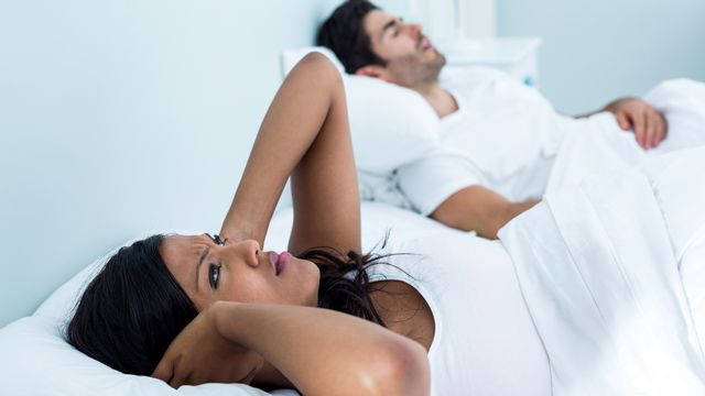 Une femme a du mal à dormir tandis que son compagnon ronfle. [Wavebreakmedia - Depositphotos]