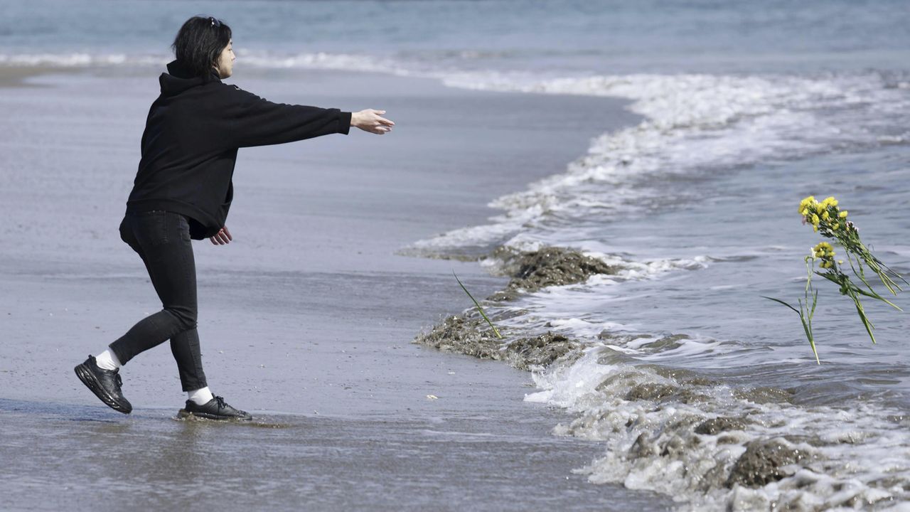 Un homme lance des fleurs à la mer à l'occasion des 12 ans de la catastrophe de Fukushima. [Kyodo News - Keystone/AP]