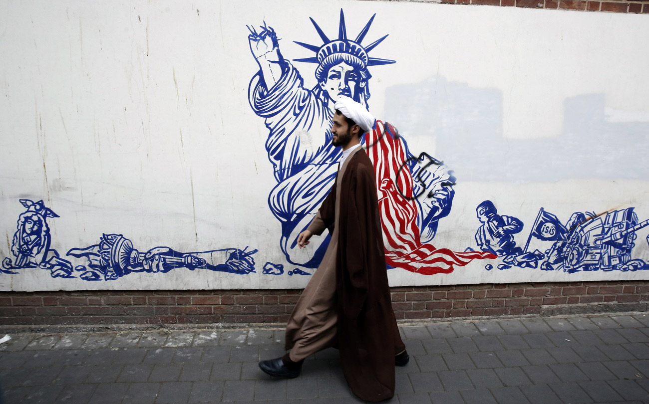 Un mollah iranien devant l'ancienne ambassade des États-Unis, à Téhéran, en novembre 2022. Derrière lui, la peinture murale marque le 43e anniversaire de la prise de contrôle de l'ambassade des États-Unis. Dès le 4 novembre 1979, après que les États-Unis ont autorisé le Shah à être hospitalisé sur leur sol, plus de 50 diplomates et gardes américains ont été retenus en otage par les étudiants durant 444 jours.