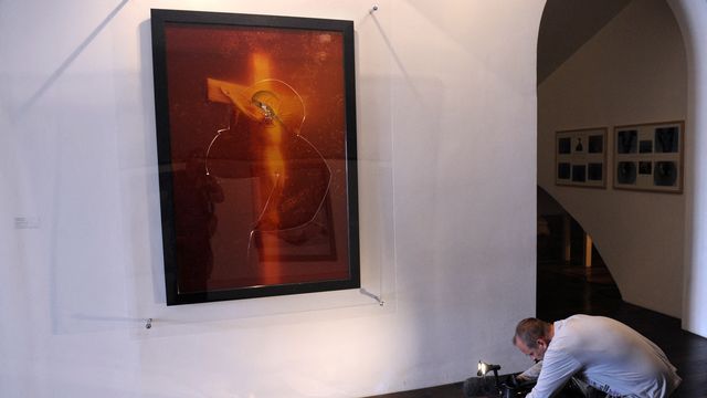 Un cameraman documente les dégâts causé à l'oeuvre "Immersion Piss Christ" de l'artiste américain Andres Serrano en avril 2011 à Avignon. [BORIS HORVAT - AFP]