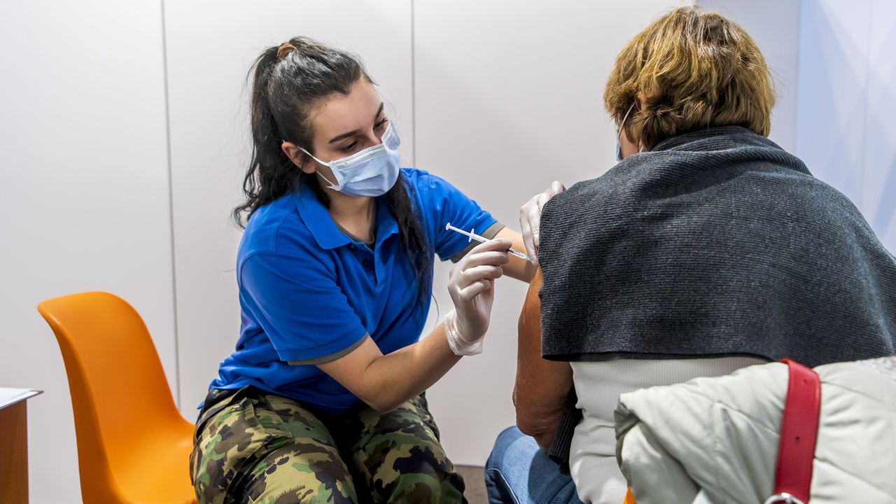 Une militaire vaccine une personne avec le vaccin moderna dans le centre de vaccination de Polyexpo le mardi 21 décembre 2021 à La Chaux-de-Fonds. [Jean-Christophe Bott - Keystone]