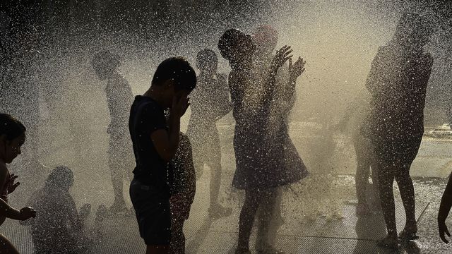 Des enfants jouant dans une fontaine à eau, au nord de l'Espagne à Pampelune. [Alvaro Barrientos - Keystone/AP Photo]
