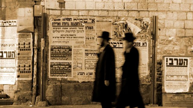 Des juifs hassidiques marchant devant des panneaux de propagande [Paulprescott - Depositphotos]