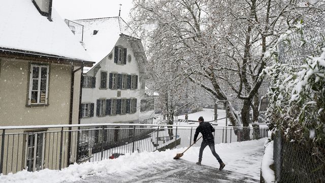 Un homme dégage une route enneigée, le jeudi 30 novembre 2023 à Berne. [Anthony Anex - Keystone]